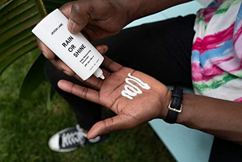 Person applying sunscreen lotion to their hand.