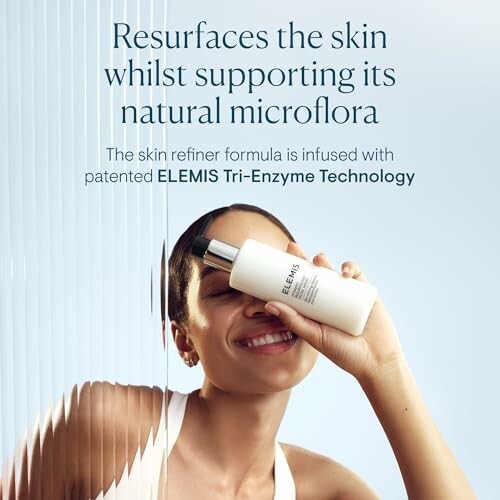 Smiling person holding Elemis skin refiner product.