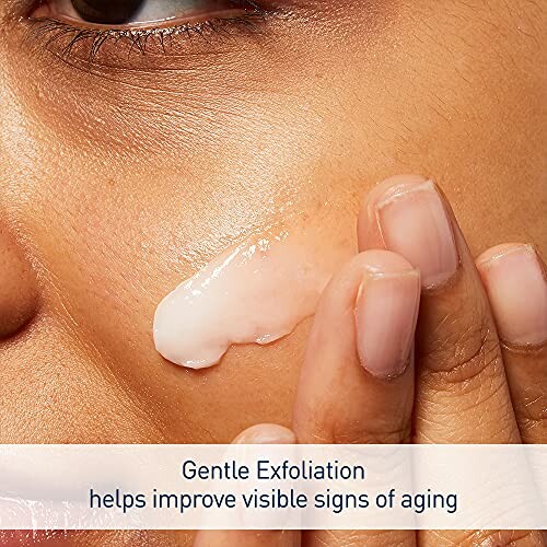 Close-up of a person applying exfoliating cream on their cheek.