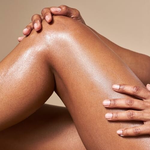 Close-up of moisturized legs and hands on beige background