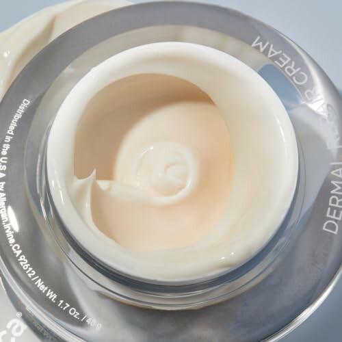 Open jar of skincare cream with beige texture