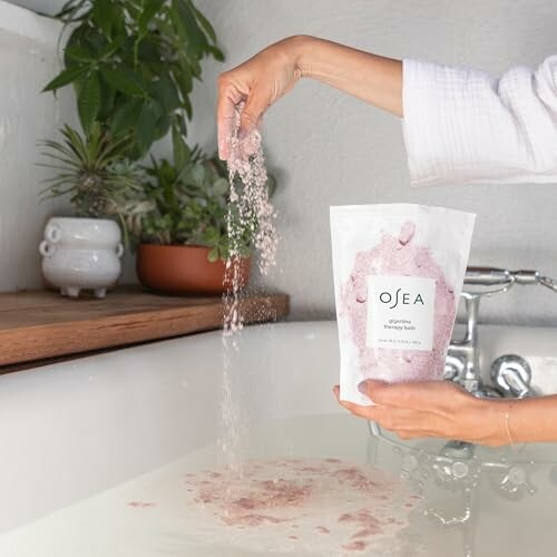 Person pouring pink bath salts into a bathtub.