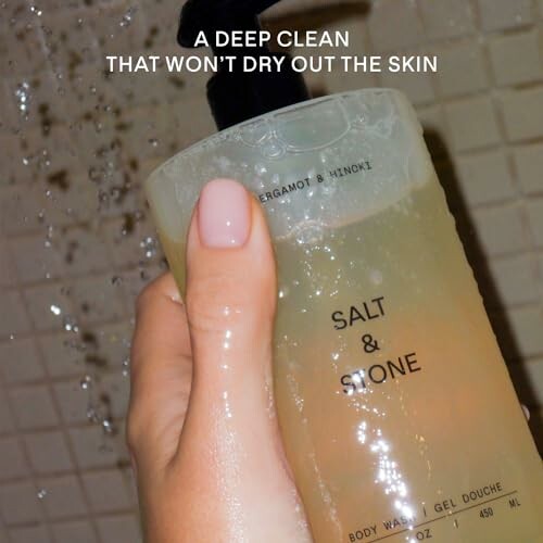 Hand holding Salt & Stone body wash in shower