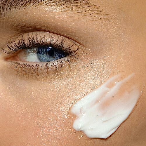 Close-up of an eye with skincare cream on the cheek