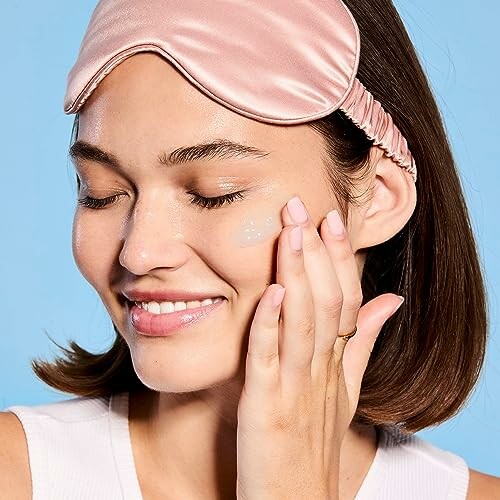 Woman applying skincare while wearing a sleep mask.