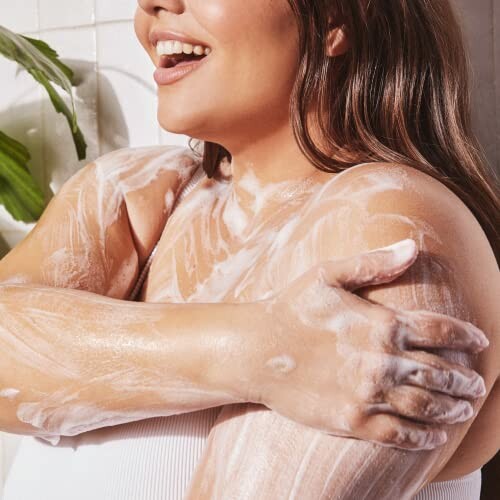 Woman applying soap on her arm in a bathroom.